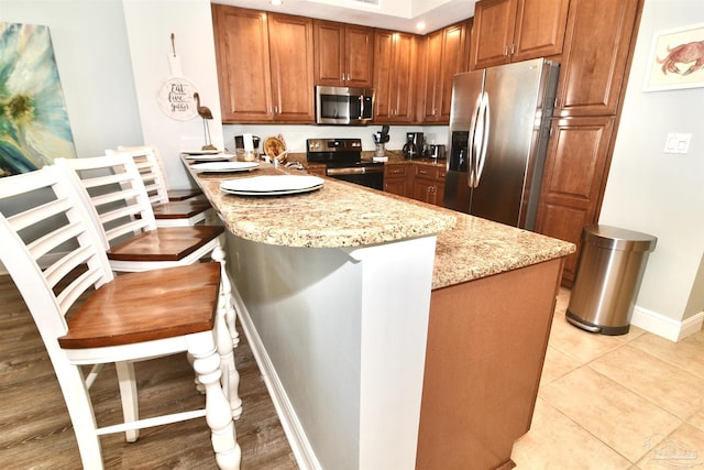 645 Lost Key Dr Unit 406D, Perdido Key, FL 32507 - kitchen featuring stainless steel appliances, light stone countertops, a peninsula, and brown cabinetry