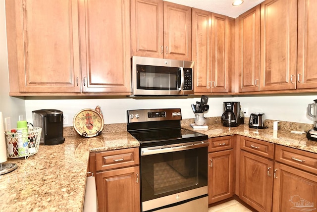645 Lost Key Dr Unit 406D, Perdido Key, FL 32507 - kitchen featuring light stone counters, brown cabinets, and stainless steel appliances