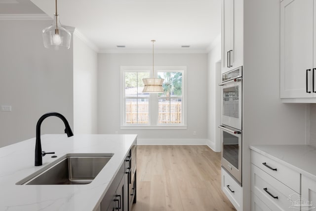 kitchen with sink, decorative light fixtures, light stone countertops, and stainless steel double oven