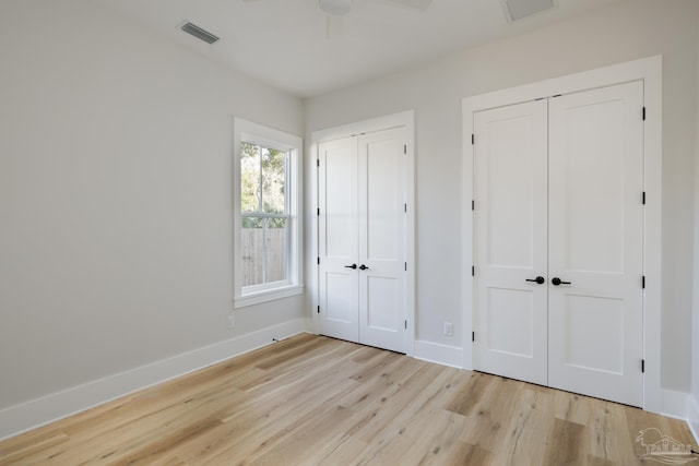 unfurnished bedroom with two closets, ceiling fan, and light wood-type flooring