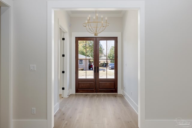 doorway with ornamental molding, a notable chandelier, light hardwood / wood-style floors, and french doors