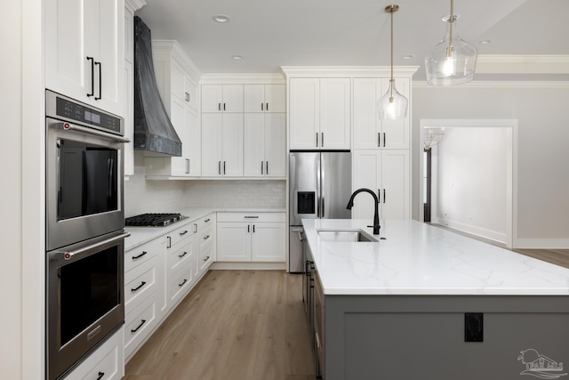 kitchen featuring hanging light fixtures, an island with sink, white cabinets, and appliances with stainless steel finishes