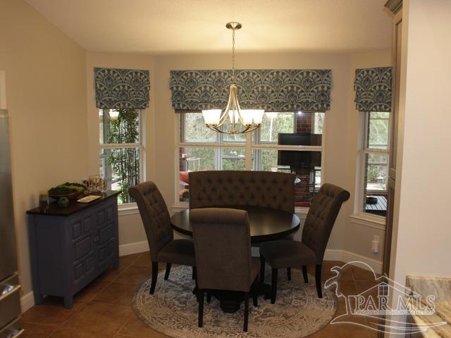 dining space featuring baseboards, tile patterned floors, and a notable chandelier