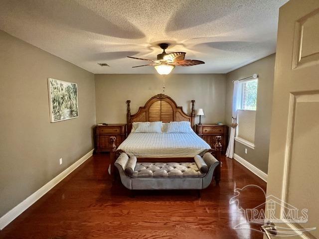 bedroom featuring baseboards, visible vents, and wood finished floors