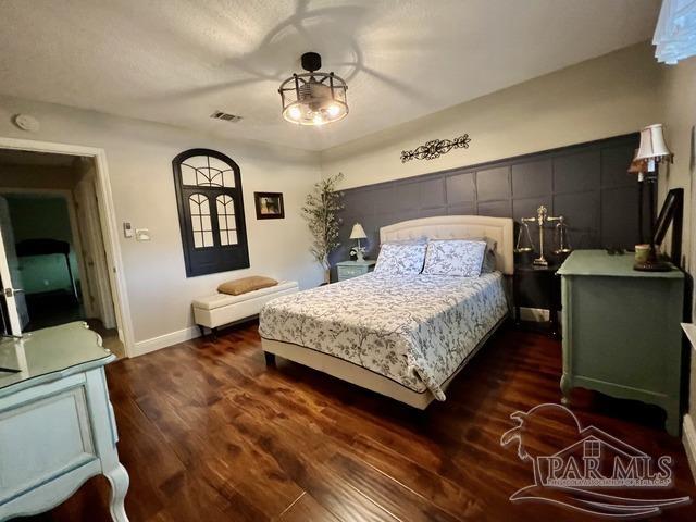 bedroom featuring baseboards, visible vents, and wood finished floors