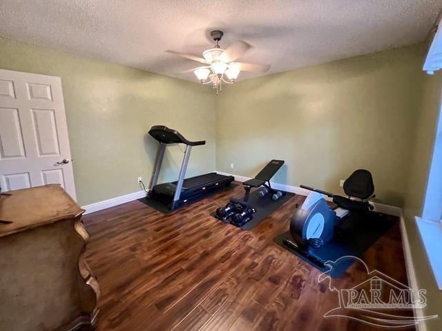 exercise area featuring a textured ceiling, ceiling fan, wood finished floors, and baseboards