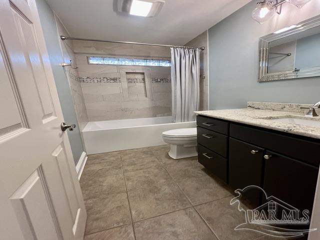 bathroom with toilet, shower / tub combo, tile patterned flooring, and vanity