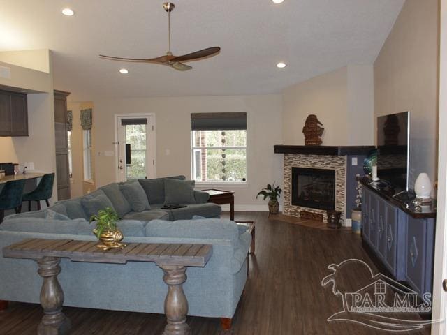 living room featuring a fireplace, a ceiling fan, vaulted ceiling, and dark wood finished floors