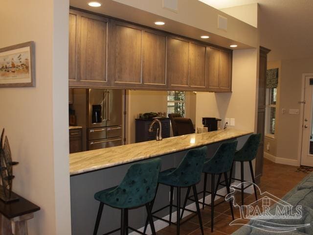 kitchen featuring a peninsula, baseboards, a breakfast bar area, and recessed lighting