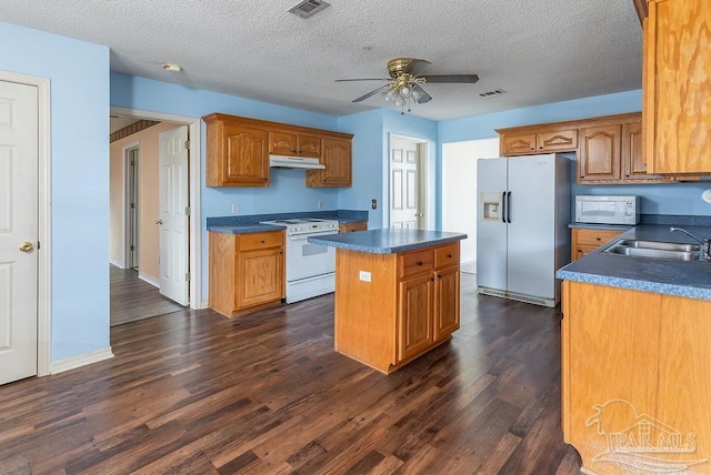 kitchen featuring white appliances, dark wood-type flooring, ceiling fan, a kitchen island, and sink