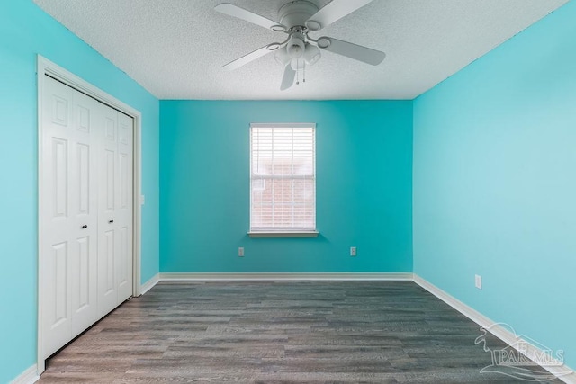 unfurnished bedroom with a textured ceiling, dark wood-type flooring, ceiling fan, and a closet