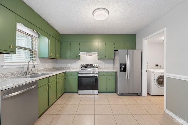 kitchen featuring appliances with stainless steel finishes, a textured ceiling, sink, light tile patterned floors, and washer / dryer