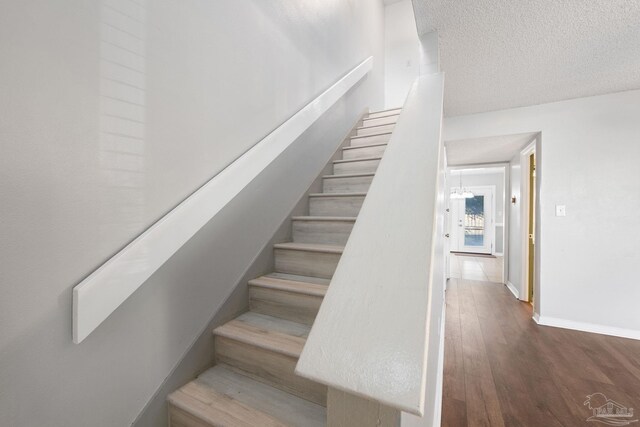 stairway featuring a textured ceiling and hardwood / wood-style flooring