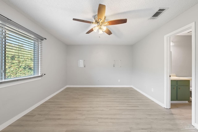 empty room with light wood-type flooring and a textured ceiling