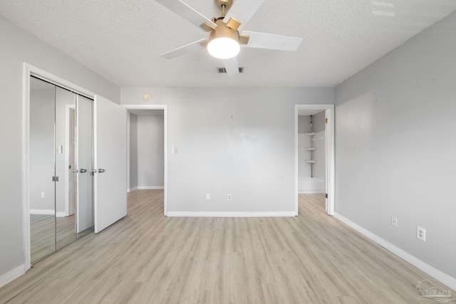 unfurnished bedroom with ceiling fan, light hardwood / wood-style floors, a textured ceiling, and a closet