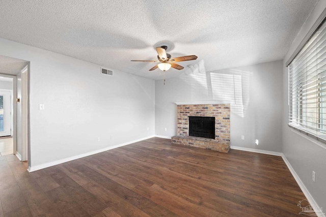 unfurnished living room with a fireplace, a textured ceiling, and dark wood-type flooring