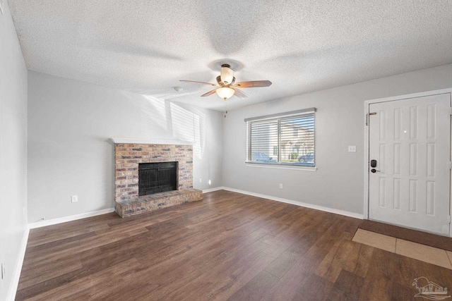 unfurnished living room featuring a textured ceiling, ceiling fan, dark hardwood / wood-style floors, and a brick fireplace