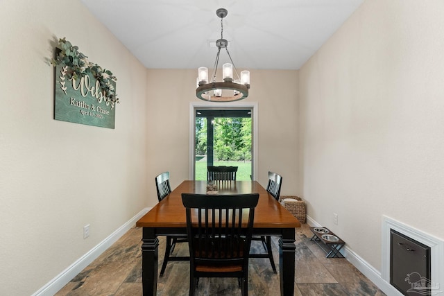 dining room with stone finish flooring, baseboards, and a chandelier