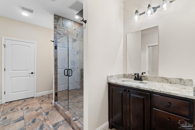 full bathroom with a stall shower, vanity, baseboards, stone finish floor, and visible vents