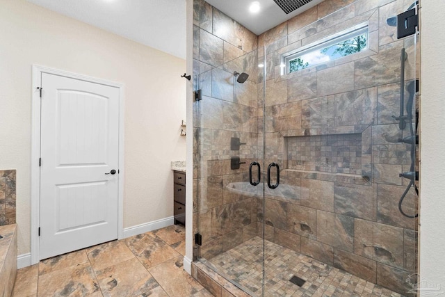 bathroom with a shower stall, baseboards, stone finish floor, and vanity