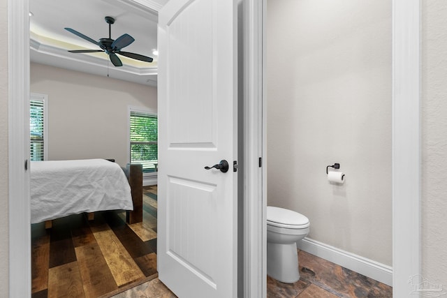 bathroom with a tray ceiling, a ceiling fan, baseboards, and toilet