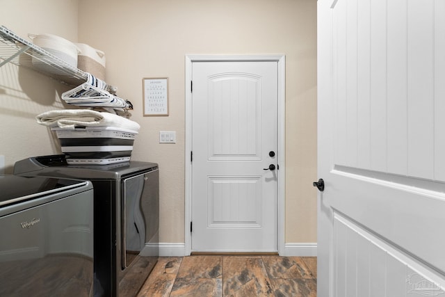 clothes washing area featuring washing machine and dryer, baseboards, wood finished floors, and laundry area