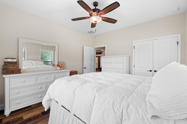 bedroom with dark wood finished floors, visible vents, a ceiling fan, and a closet