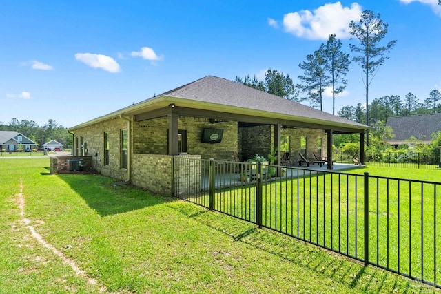 view of side of home featuring central air condition unit, brick siding, fence private yard, ceiling fan, and a yard