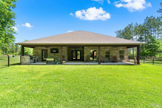 rear view of property with a fenced backyard, a lawn, ceiling fan, and french doors