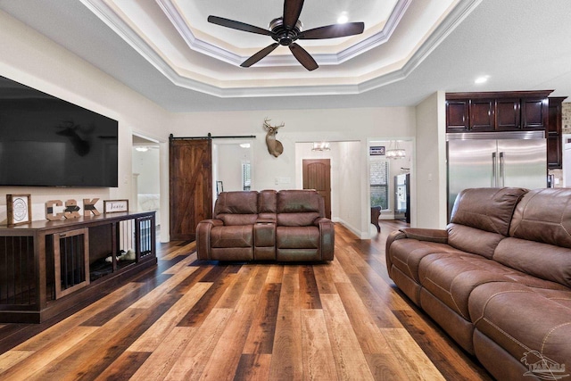 living room featuring ceiling fan, ornamental molding, a barn door, and light wood-style floors