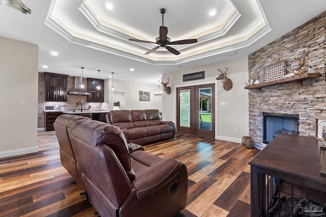 living area featuring a raised ceiling, a ceiling fan, crown molding, and french doors
