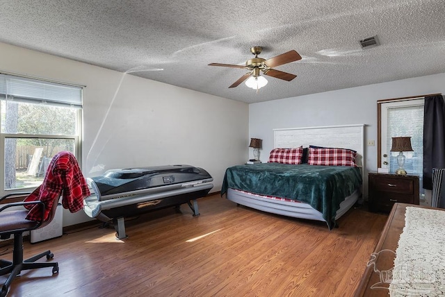 bedroom with a textured ceiling, visible vents, and wood finished floors