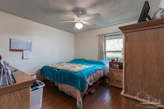 bedroom with a textured ceiling, ceiling fan, and dark wood-type flooring