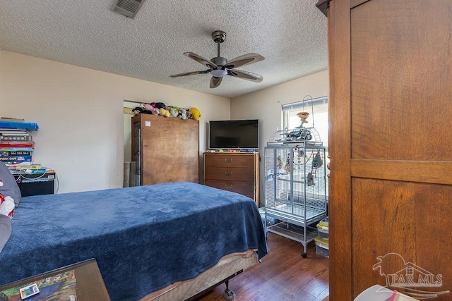 bedroom featuring visible vents, ceiling fan, a textured ceiling, and wood finished floors