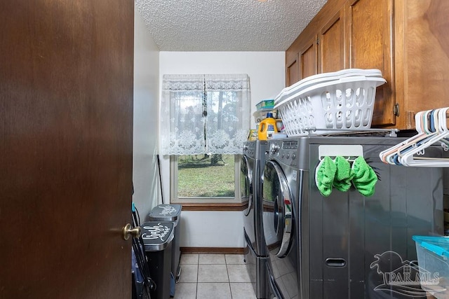 washroom featuring light tile patterned floors, a textured ceiling, separate washer and dryer, baseboards, and cabinet space