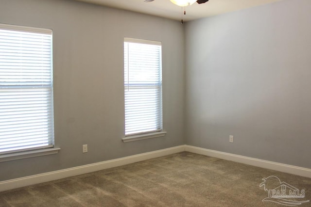 carpeted spare room featuring a wealth of natural light and ceiling fan