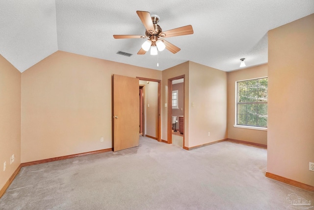 carpeted empty room with ceiling fan, lofted ceiling, and a textured ceiling