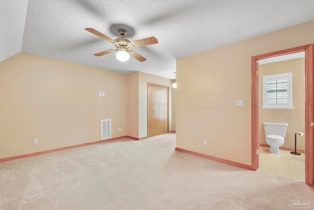 carpeted empty room featuring vaulted ceiling, ceiling fan, and a textured ceiling