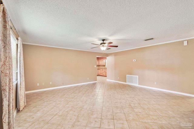 tiled empty room with a textured ceiling, a large fireplace, ceiling fan, and crown molding