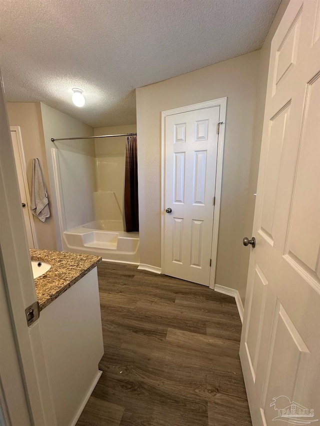 bathroom featuring vanity, hardwood / wood-style floors, a textured ceiling, and shower / bath combination with curtain