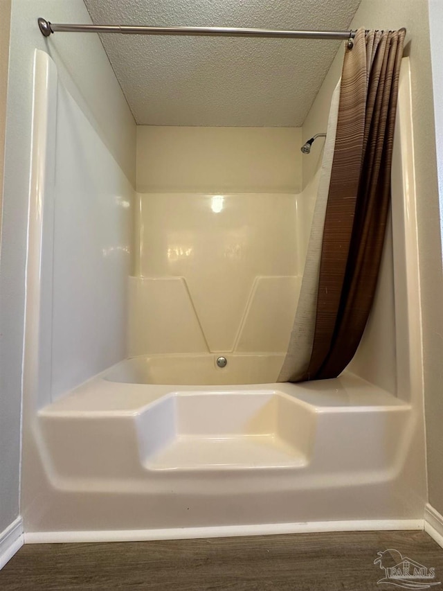 bathroom with hardwood / wood-style floors, a textured ceiling, and curtained shower