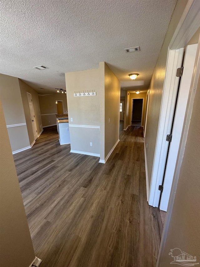 hallway with dark wood-type flooring and a textured ceiling