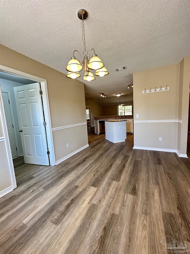 interior space featuring dark wood-type flooring, a chandelier, and a textured ceiling