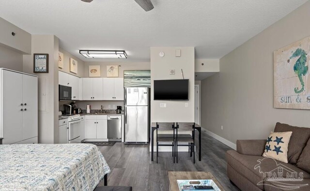 interior space with appliances with stainless steel finishes, sink, dark wood-type flooring, and white cabinets