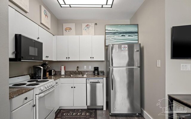 kitchen featuring dark stone counters, dark hardwood / wood-style flooring, white cabinetry, appliances with stainless steel finishes, and sink