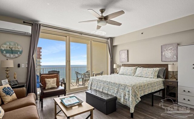 bedroom with a water view, access to outside, ceiling fan, a wall mounted AC, and hardwood / wood-style flooring