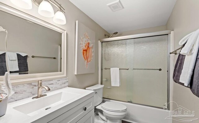 full bathroom with decorative backsplash, vanity, bath / shower combo with glass door, and toilet