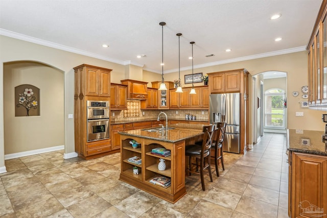 2882 Tunnel Rd, Pace, FL 32571 - kitchen featuring stainless steel appliances, arched walkways, brown cabinetry, dark stone countertops, and decorative backsplash