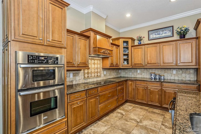 2882 Tunnel Rd, Pace, FL 32571 - kitchen with stainless steel double oven, black electric cooktop, brown cabinetry, dark stone counters, and decorative backsplash