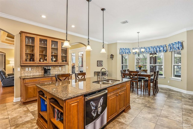 2882 Tunnel Rd, Pace, FL 32571 - kitchen with stainless steel dishwasher, brown cabinetry, dark stone counters, a kitchen island with sink, and decorative backsplash